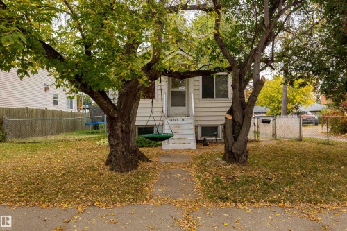 Exterior featuring a white siding facade, white-painted porch steps, and a chain-link fence - 12707 73 Street Nw, Edmonton, AB 