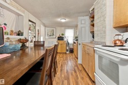 Wood-finish flooring, white paneled walls, wood cabinetry, and a built-in oven - 