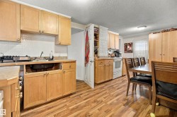 Wood-finish flooring throughout, light wood-tone cabinetry, white subway tile backsplash, recessed shelving, and a dining area - 