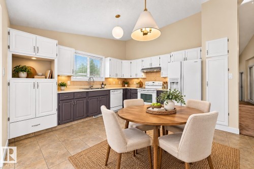 Kitchen featuring two-tone cabinetry, a stainless steel sink, white appliances, and tiled flooring - 7307 152C Avenue Nw, Edmonton, AB 