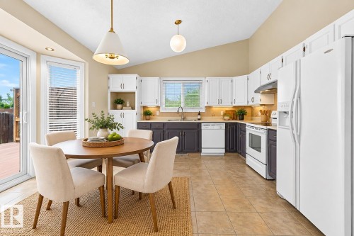 Kitchen featuring white appliances, a vaulted ceiling, recessed lighting, and a sliding glass door - 7307 152C Avenue Nw, Edmonton, AB 