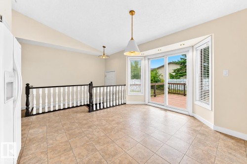 Tiled flooring throughout, vaulted ceiling, and sliding glass door leading to an exterior deck - 7307 152C Avenue Nw, Edmonton, AB 