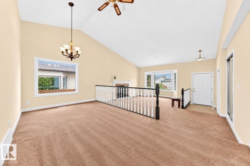 Vaulted ceiling, ceiling fan, fireplace, chandelier, and a white front entry door - 7307 152C Avenue Nw, Edmonton, AB 