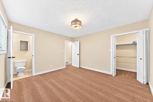Plush brown carpeting, neutral wall paint, ceiling light fixture, bi-fold closet doors, and window with blinds - 7307 152C Avenue Nw, Edmonton, AB 