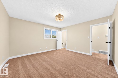 Carpeted interior with light-colored walls, white trim, and a ceiling-mounted light fixture - 7307 152C Avenue Nw, Edmonton, AB 