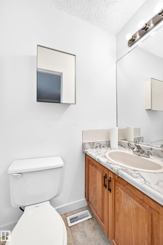 Recessed lighting fixture, vanity with wood-finish cabinetry, integrated sink, and wall-mounted mirror - 7307 152C Avenue Nw, Edmonton, AB 