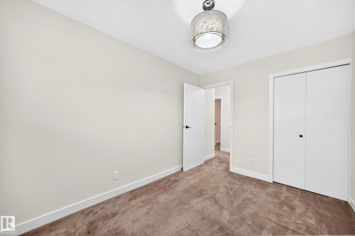 Neutral wall paint, brown carpeting, white trim, white interior doors, and a ceiling-mounted light fixture - 7307 152C Avenue Nw, Edmonton, AB 