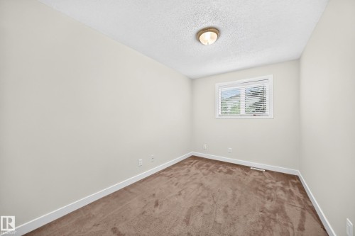 Neutral wall paint with carpeted flooring, a single window with blinds, and an overhead light fixture - 7307 152C Avenue Nw, Edmonton, AB 
