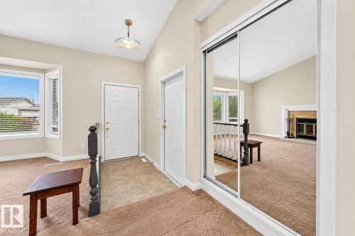 Entryway featuring a decorative front door, tiled flooring, bay window, and mirrored sliding closet doors - 7307 152C Avenue Nw, Edmonton, AB 