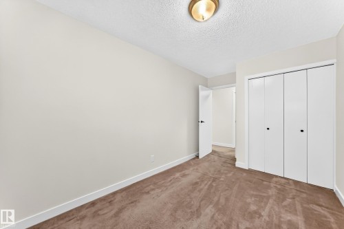 Neutral painted walls with a textured ceiling and a ceiling-mounted light fixture - 7307 152C Avenue Nw, Edmonton, AB 
