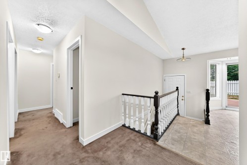 Staircase with contrasting dark and white balusters, tiled flooring, and a panel door entry - 7307 152C Avenue Nw, Edmonton, AB 