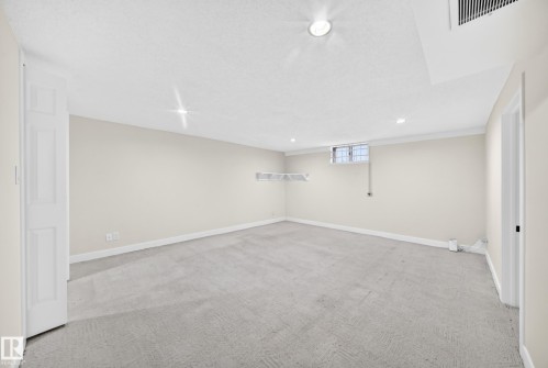 Recessed lighting, wall-to-wall carpeting, crown molding, casement window with security bars, and white wire shelving - 7307 152C Avenue Nw, Edmonton, AB 