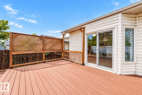 Expansive exterior deck with wood-finish decking, lattice privacy screen, and white vinyl siding - 7307 152C Avenue Nw, Edmonton, AB 