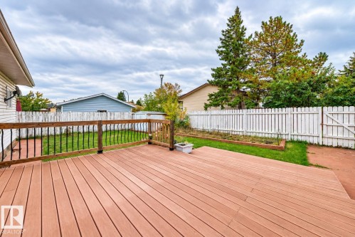 Expansive outdoor deck featuring wood-finish composite decking and a wooden railing with black metal spindles - 7307 152C Avenue Nw, Edmonton, AB 