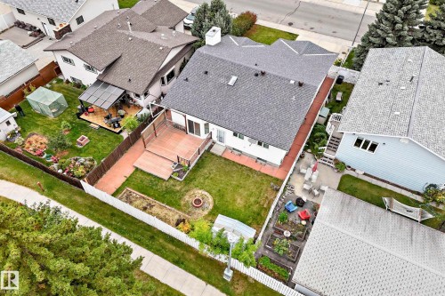 Rear exterior featuring a large wooden deck, covered patio, fire pit, and raised garden beds - 7307 152C Avenue Nw, Edmonton, AB 