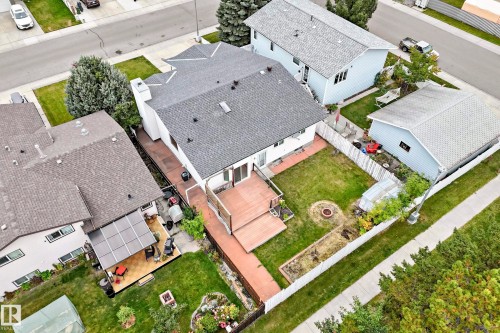 Expansive backyard with a two-tiered wood-finish deck, manicured lawn, and a fire pit - 7307 152C Avenue Nw, Edmonton, AB 
