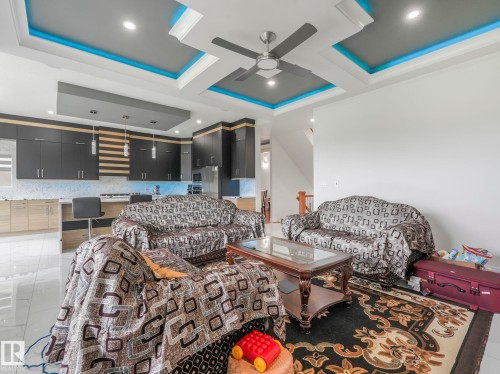 Recessed ceiling lighting, ceiling fan, contemporary kitchen cabinetry, built-in kitchen island, and polished tile flooring - 120 38 Street Sw, Edmonton, AB 