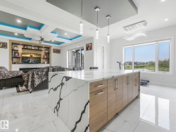 Waterfall island with stone-finish countertop, wood-finish cabinetry, and contemporary pendant lighting - 
