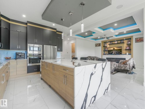 Gourmet kitchen with stainless steel appliances, two-tone cabinetry, and a waterfall-edge island - 120 38 Street Sw, Edmonton, AB 