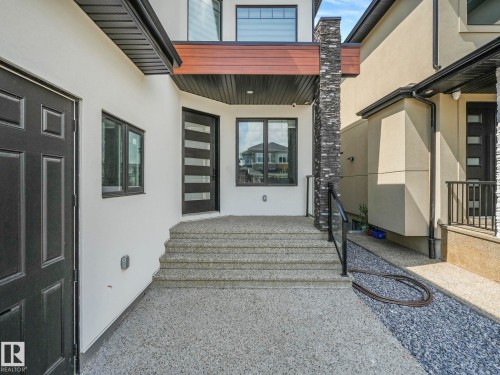 White stucco exterior with a prominent stone-clad pillar - 120 38 Street Sw, Edmonton, AB 