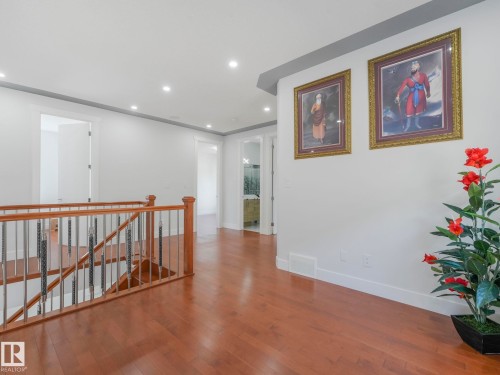 Hardwood flooring, recessed lighting, white walls, dark gray crown molding, and a staircase with wood and metal railing - 120 38 Street Sw, Edmonton, AB 