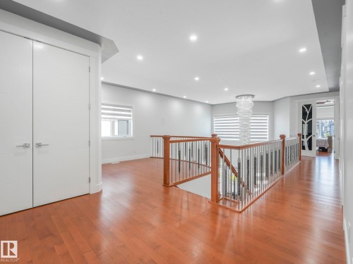 Hardwood flooring, recessed lighting, contemporary chandelier, white paneled doors, and a staircase with wood newel posts and metal spindles - 120 38 Street Sw, Edmonton, AB 