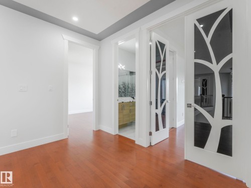 Hardwood flooring throughout, recessed lighting, modern doors with decorative glass inserts, and a contemporary vanity with a vessel sink - 120 38 Street Sw, Edmonton, AB 