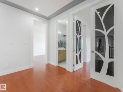 Hardwood flooring throughout, recessed lighting, modern doors with decorative glass inserts, and a contemporary vanity with a vessel sink - 