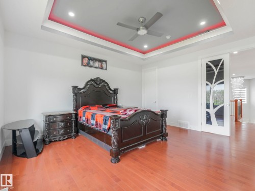 Tray ceiling with recessed lighting, integrated ceiling fan, wood-finish flooring, and a decorative sliding door with frosted glass - 120 38 Street Sw, Edmonton, AB 