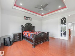 Tray ceiling with recessed lighting, integrated ceiling fan, wood-finish flooring, and a decorative sliding door with frosted glass - 