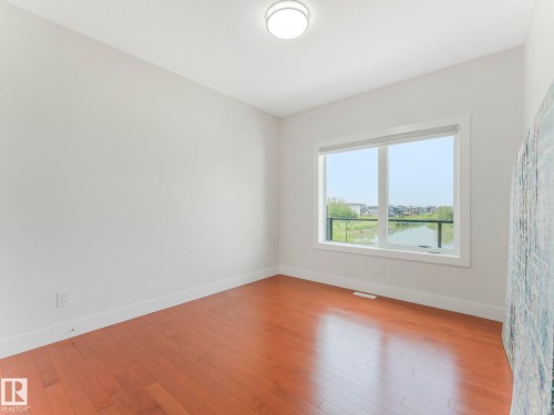 Hardwood flooring throughout, white baseboards, white walls, large window, and ceiling-mounted light fixture - 120 38 Street Sw, Edmonton, AB 