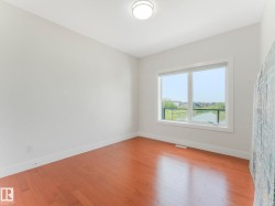 Hardwood flooring throughout, white baseboards, white walls, large window, and ceiling-mounted light fixture - 