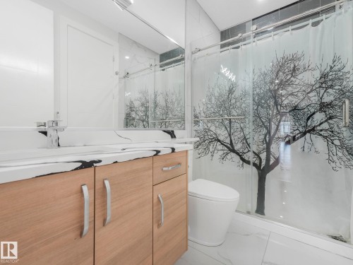 Wood-finish vanity with chrome hardware, integrated sink, and a white countertop with black veining - 120 38 Street Sw, Edmonton, AB 
