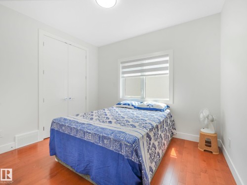 Hardwood flooring, white window trim, dual-pane window, white roller blinds, and a white flush-mount ceiling light - 120 38 Street Sw, Edmonton, AB 