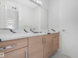 Double vanity with light wood-finish cabinetry and chrome hardware - 