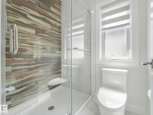 Glass-enclosed shower with decorative wall tiling, white shower pan, and chrome fixtures - 120 38 Street Sw, Edmonton, AB 