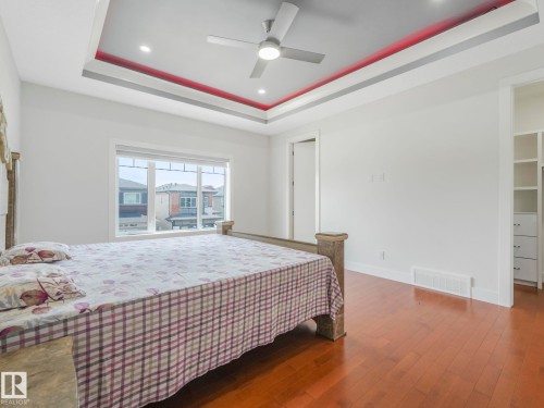 Tray ceiling with integrated lighting, wood-finish flooring, ceiling fan, and large window - 120 38 Street Sw, Edmonton, AB 