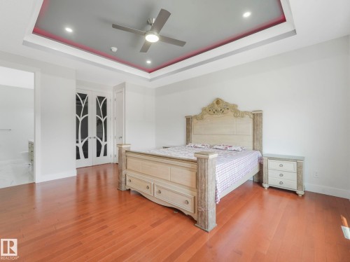 Tray ceiling with recessed lighting, ceiling fan, wood-finish flooring, and white French doors with decorative glass panels - 120 38 Street Sw, Edmonton, AB 