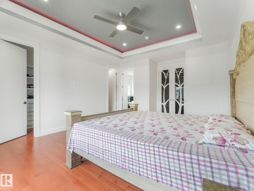 Recessed lighting, wood-finish flooring, tray ceiling with a ceiling fan, and double doors with decorative frosted glass - 120 38 Street Sw, Edmonton, AB 