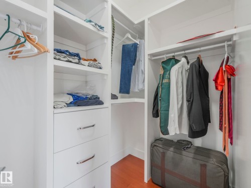 Built-in closet system featuring white shelving, multiple hanging rods, and integrated drawers with polished chrome hardware - 120 38 Street Sw, Edmonton, AB 