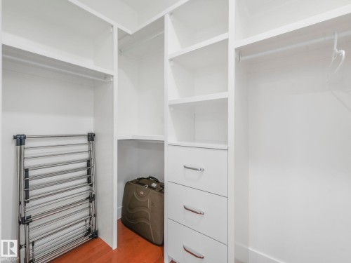 Built-in white cabinetry featuring multiple shelving units, integrated drawers with metal hardware, and hanging rods - 120 38 Street Sw, Edmonton, AB 