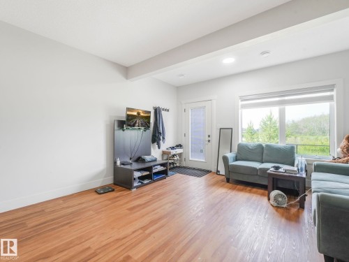 Wood-finish flooring throughout, with a white painted interior and a large window offering natural scenery - 120 38 Street Sw, Edmonton, AB 