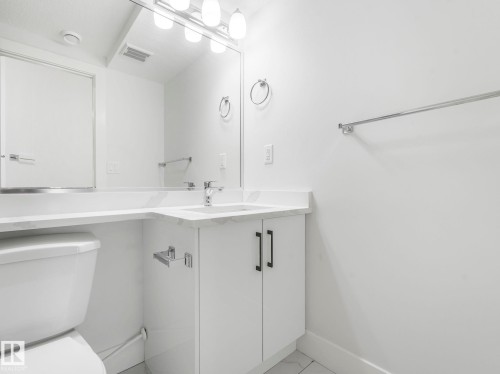 White vanity with a rectangular undermount sink, a chrome faucet, and a large wall-mounted mirror - 120 38 Street Sw, Edmonton, AB 