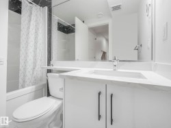 White vanity with a built-in sink and stone-finish countertop, chrome faucet, and dark cabinet hardware - 