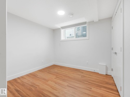 Recessed ceiling lighting, wood-finish flooring, white trim, white door with brushed nickel hardware, and a window with white casing - 120 38 Street Sw, Edmonton, AB 