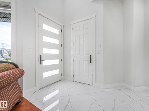White paneled interior doors, modern frosted glass front entry door, and large-format tile flooring - 120 38 Street Sw, Edmonton, AB 