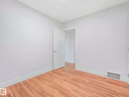 Light gray walls, wood-finish flooring, white trim, and a white interior door - 120 38 Street Sw, Edmonton, AB 