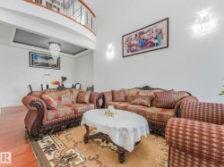 Hardwood flooring, recessed ceiling with chandelier, curved balcony with metal balusters, and wall-mounted sconces - 