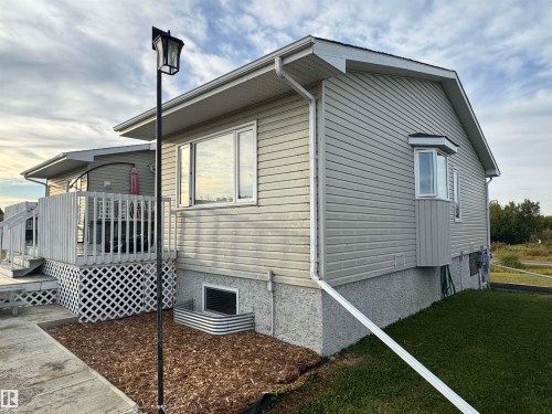 Light-toned siding exterior with multiple windows, a bay window, and a rear deck with lattice skirting - 20120 Twp Rd 515, Rural Beaver County, AB 