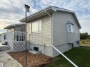 Light-toned siding exterior with multiple windows, a bay window, and a rear deck with lattice skirting - 20120 Twp Rd 515, Rural Beaver County, AB 